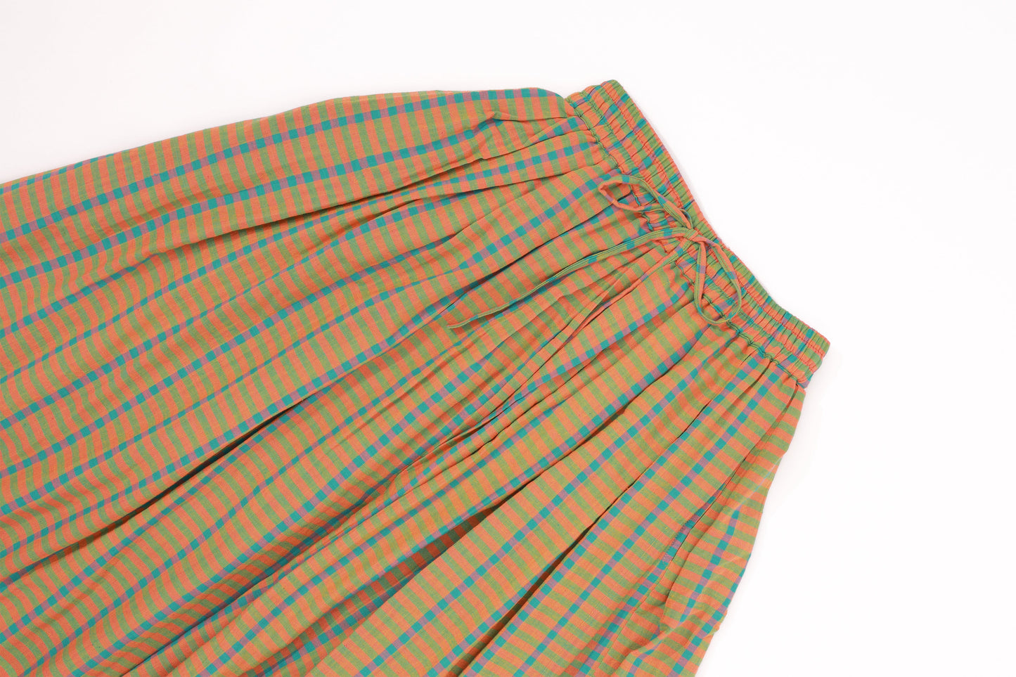 Plains Design - Twin skirt in Orange. Closeup of waist and top portion of a midi skirt in orange and blue checks with a relaxed fit. Drawstring waist. Ethically handmade with handspun cotton in India.