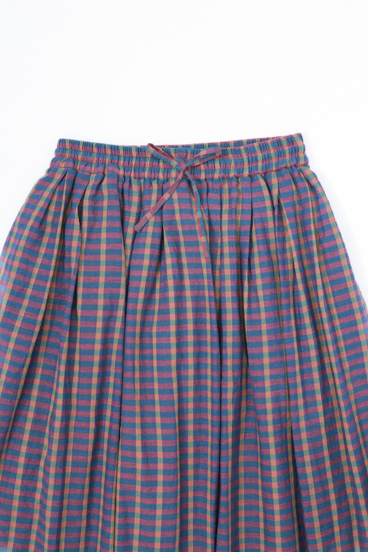 Plains Design - Twin Skirt in Purple. Close up of waist and front of purple and blue striped plaid skirt with pockets and a tie waist. Handspun cotton fabric.
