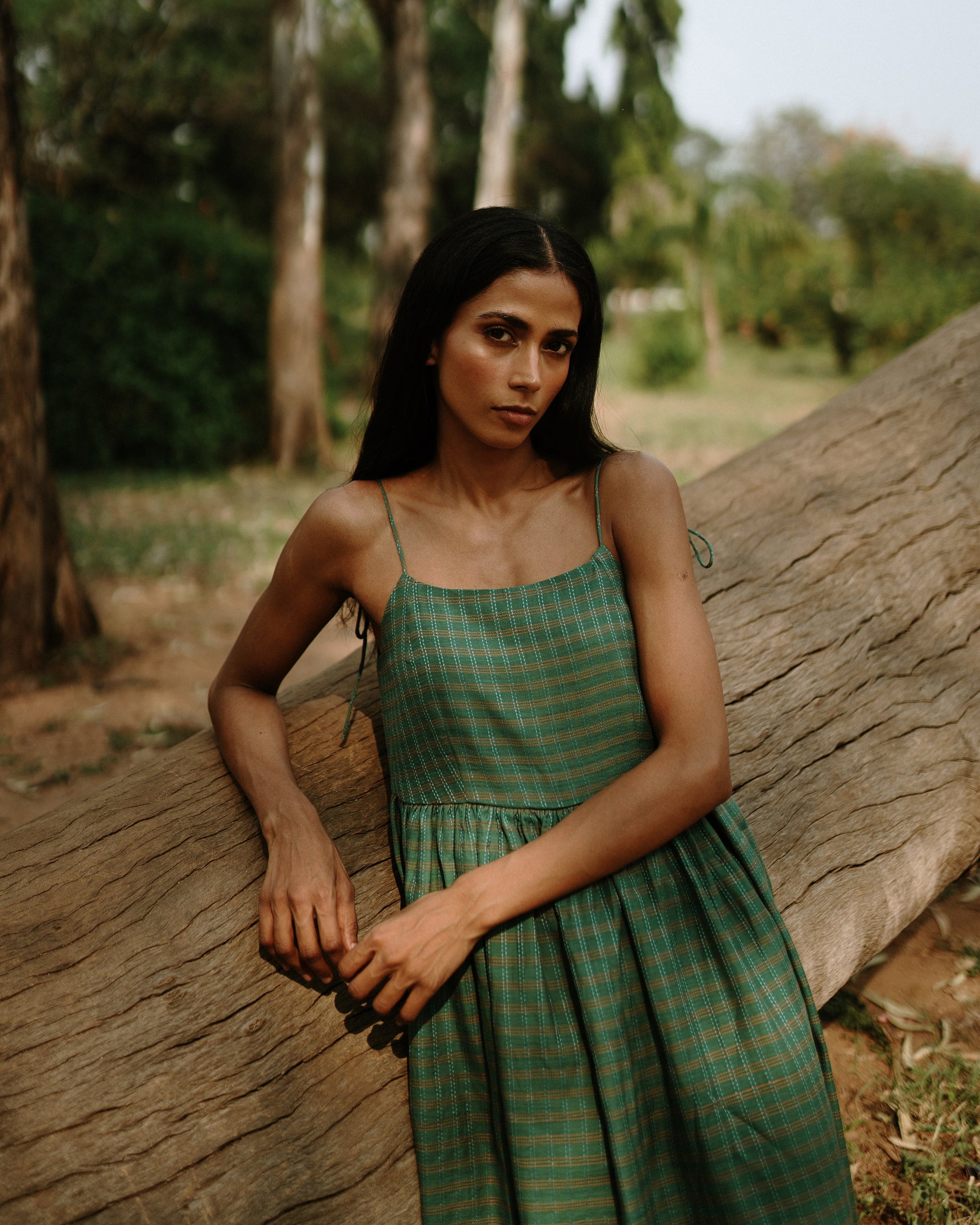 Plains Design - River mulberry silk cotton dress. Sleeveless midi dress with spaghetti straps, and a gathered waist in a green cotton mulberry silk fabric with red and white checks. Ethically handmade and handspun in India.