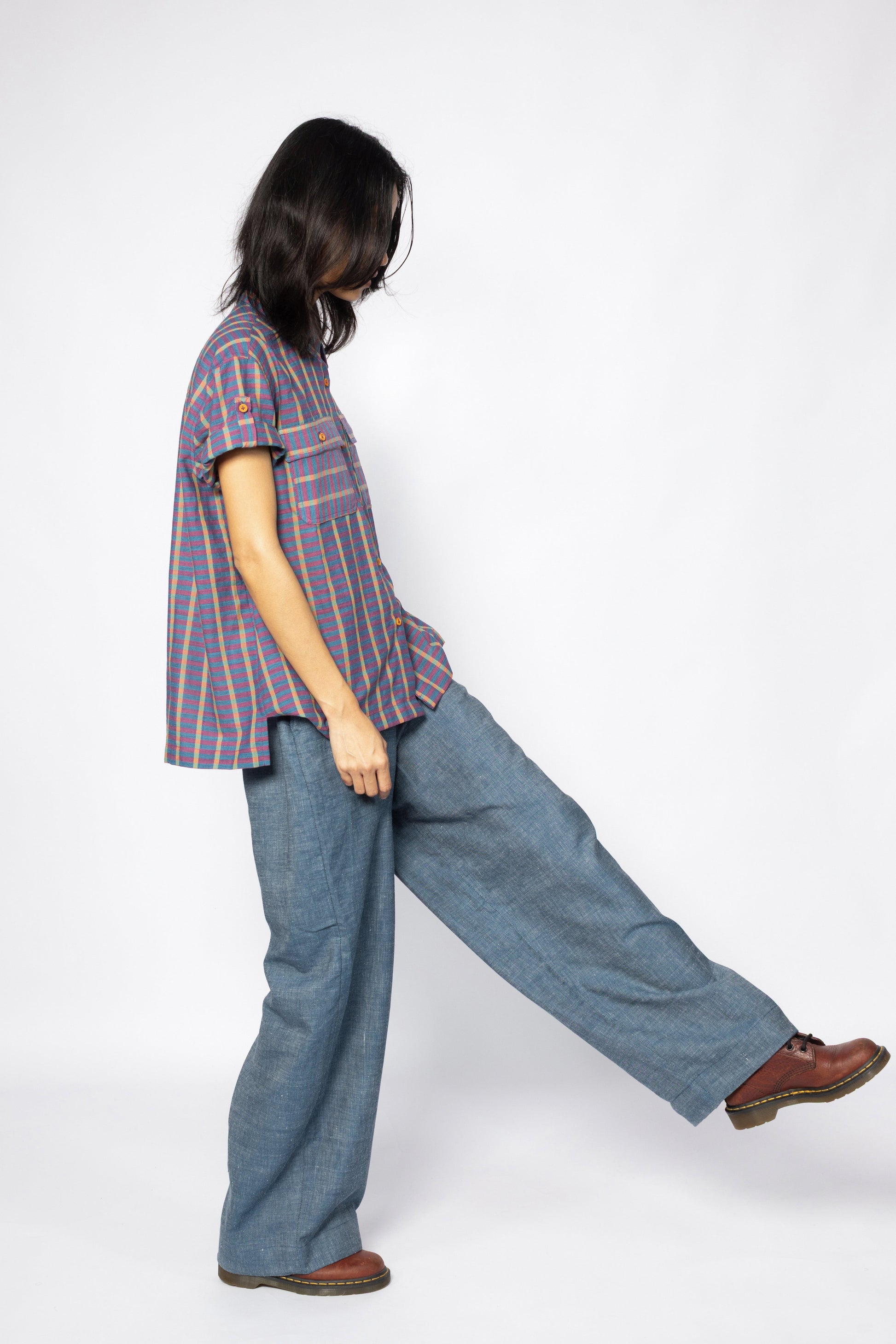 Plains Design Billie Denim Pants – handwoven cotton denim wide-leg pants in mid blue, oversized fit, styled with a short-sleeved stripe shirt