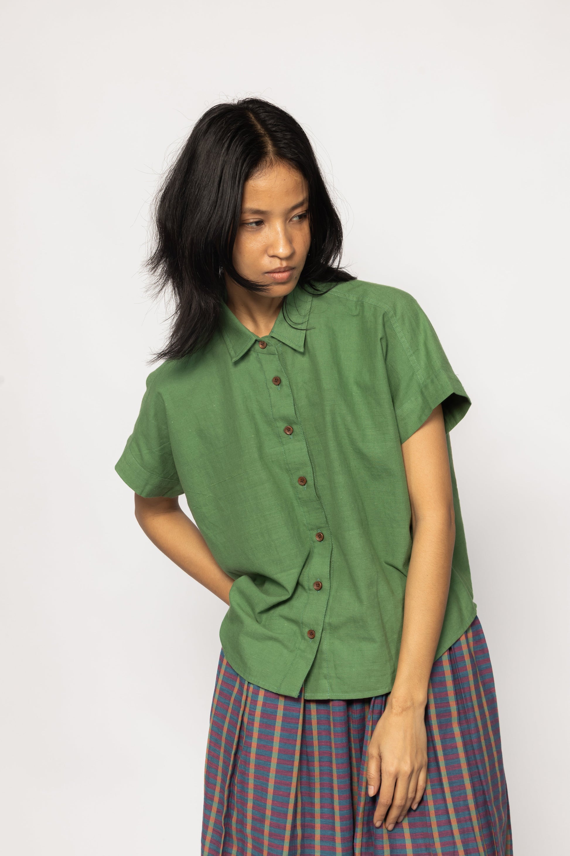 Plains Design - Bud Shirt. Bright green short sleeved shirt with wooden buttons paired with a skirt. Handwoven cotton. Sustainable fashion