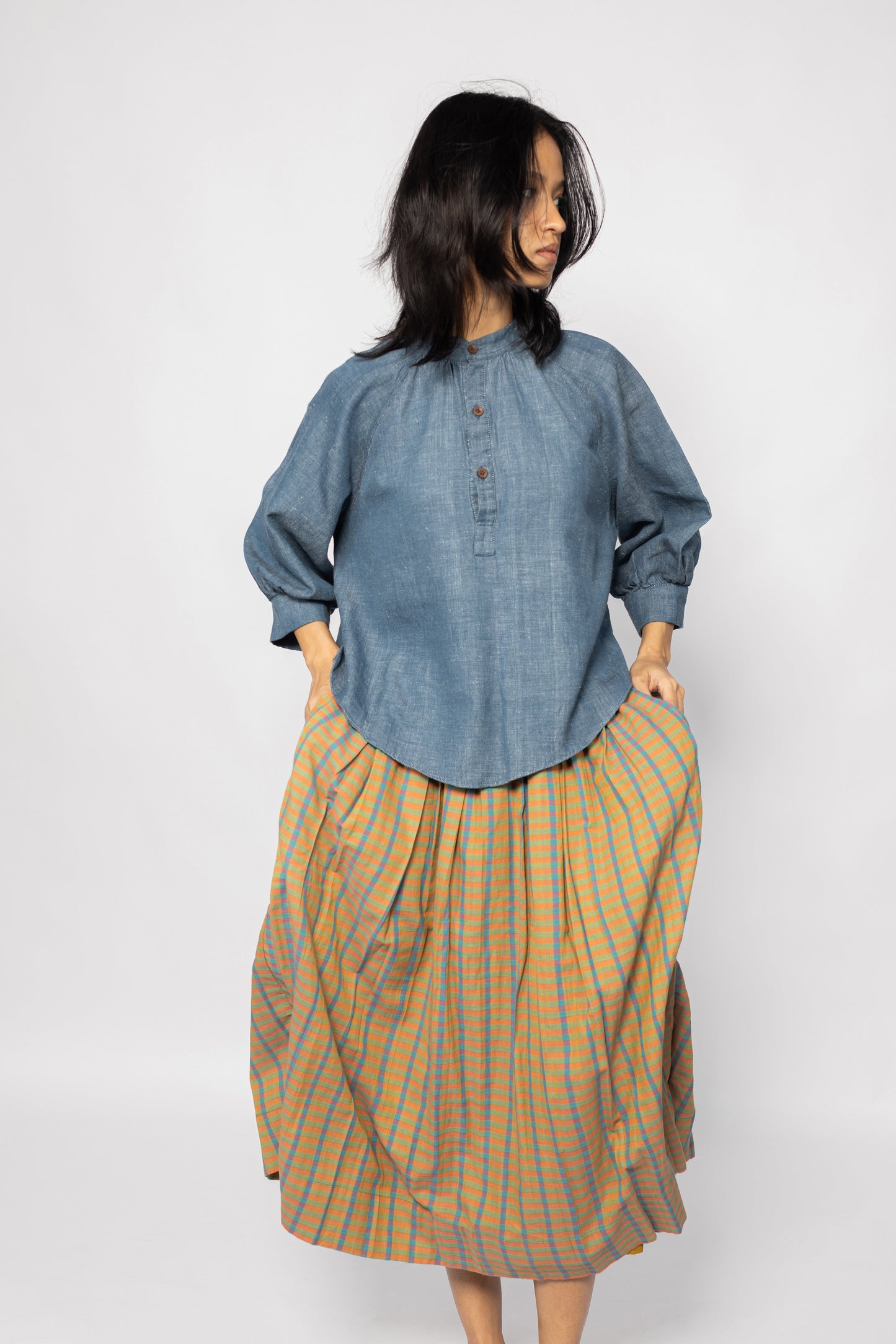 Plains Design - Twin skirt in Orange. Midi skirt with orange, blue and yellow checks in a relaxed fit and side pockets. Paired with a denim top. Ethically handmade with handspun cotton in India.