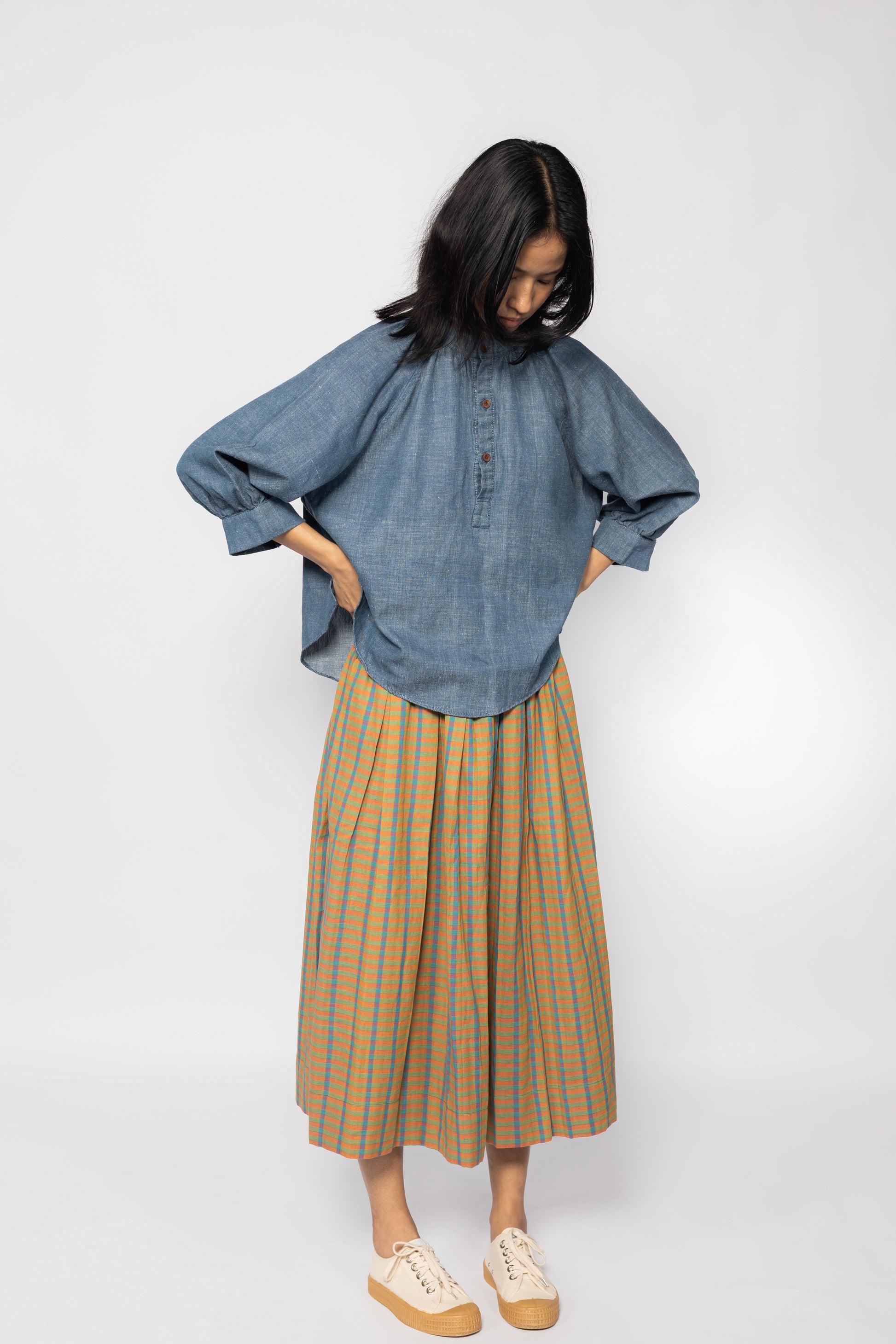 Plains Design - Twin skirt in Orange. Midi skirt with orange, blue and yellow checks in a relaxed fit and side pockets. Paired with a denim top. Ethically handmade with handspun cotton in India.