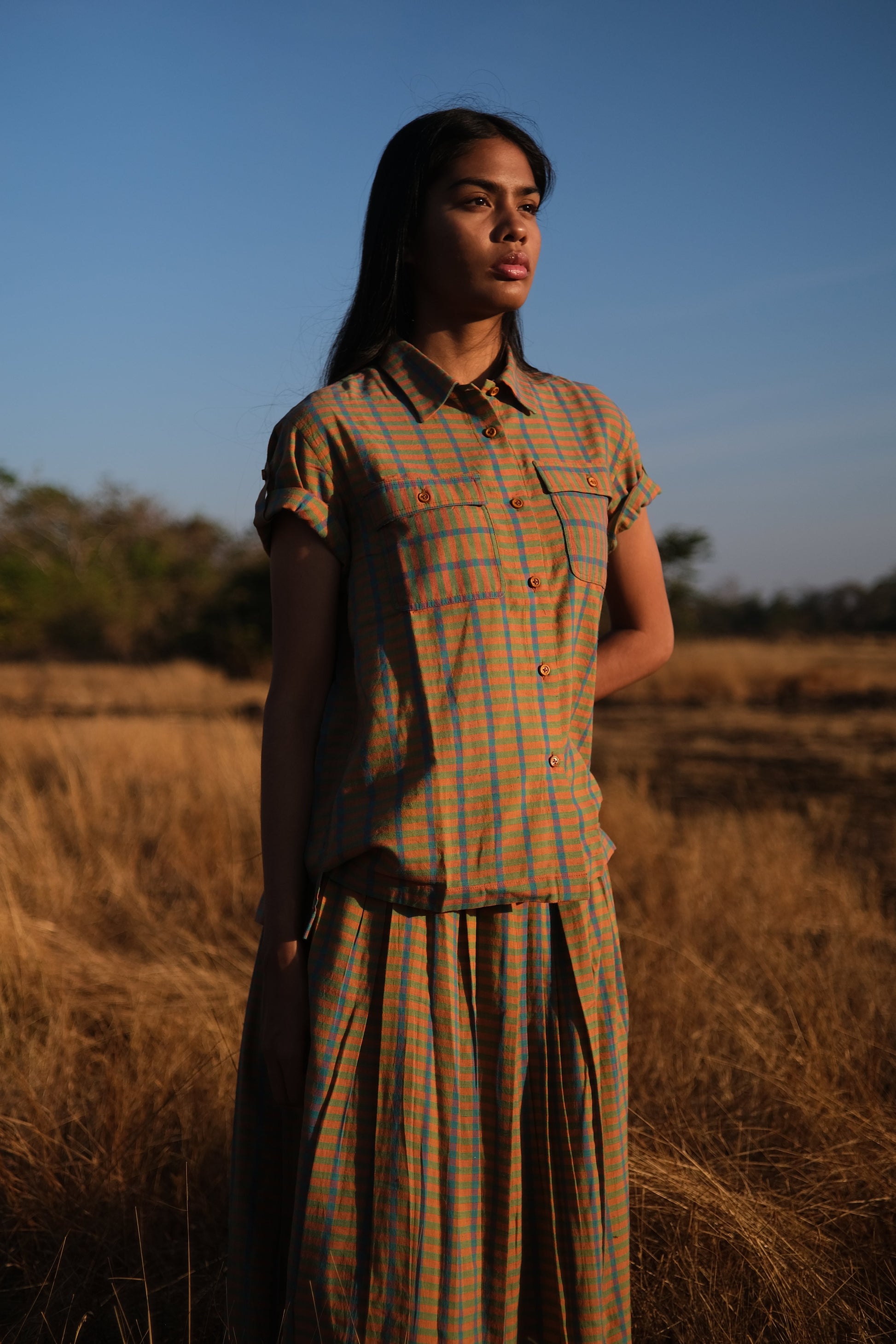 Plains Design - Twin shirt in orange. Orange and blue checkered shirt with short folded sleeves, two chest pockets and wooden buttons in a straight relaxed fit. Ethically handmade cotton.