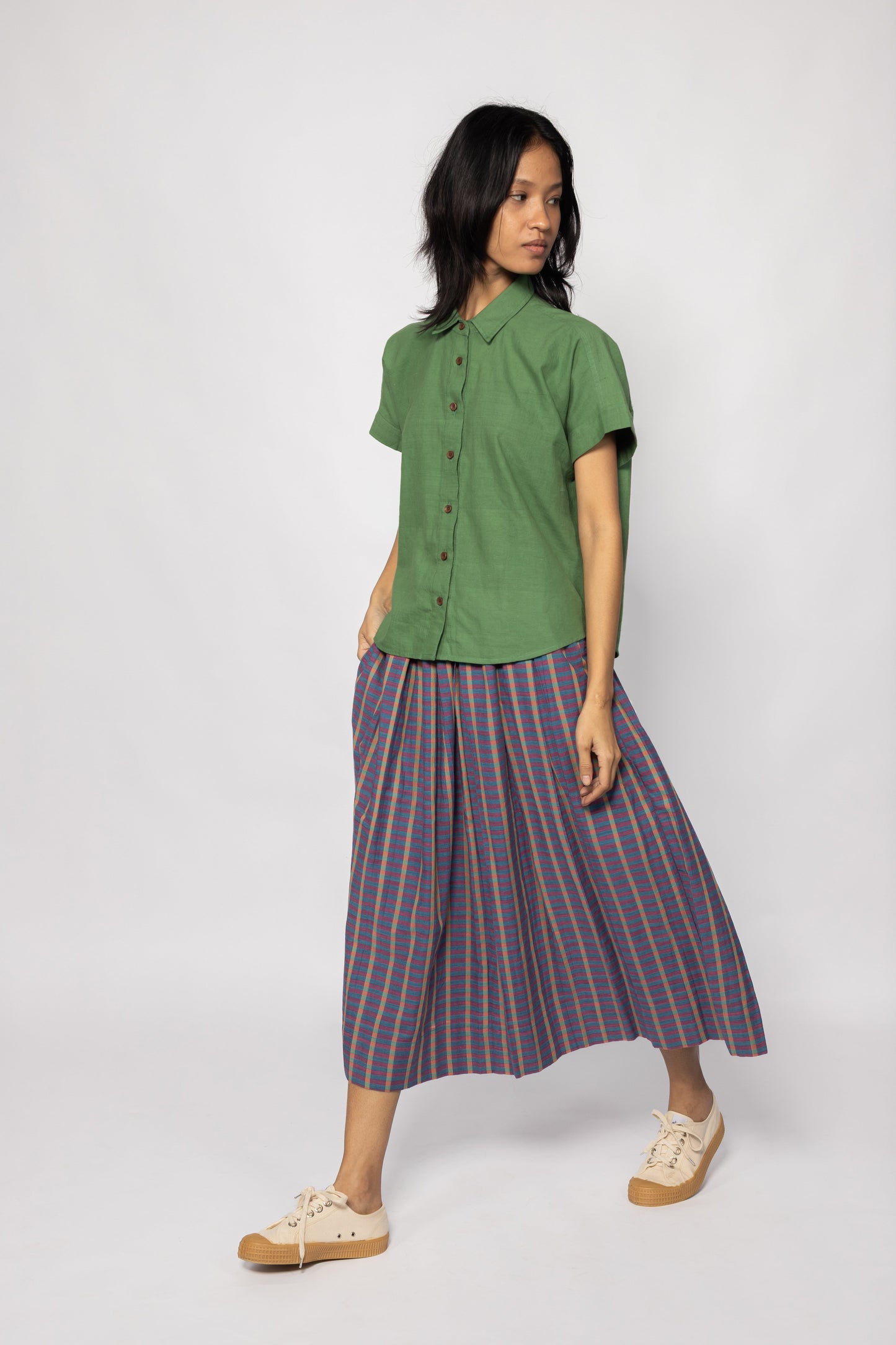 Plains Design - Twin Skirt in Purple. Model walking in purple striped skirt with pockets paired with a green shirt and canvas shoes. Handmade cotton. Ethical fashion.