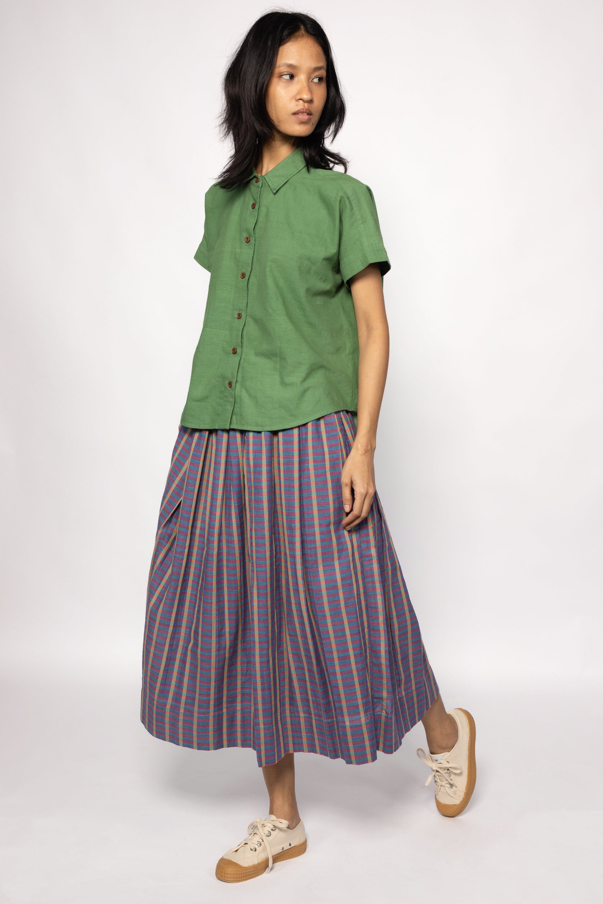 Plains Design - Twin Skirt in Purple. Woman walking in purple and blue striped skirt with pockets, paired with a green shirt and canvas shoes. Handmade cotton. Ethical fashion.