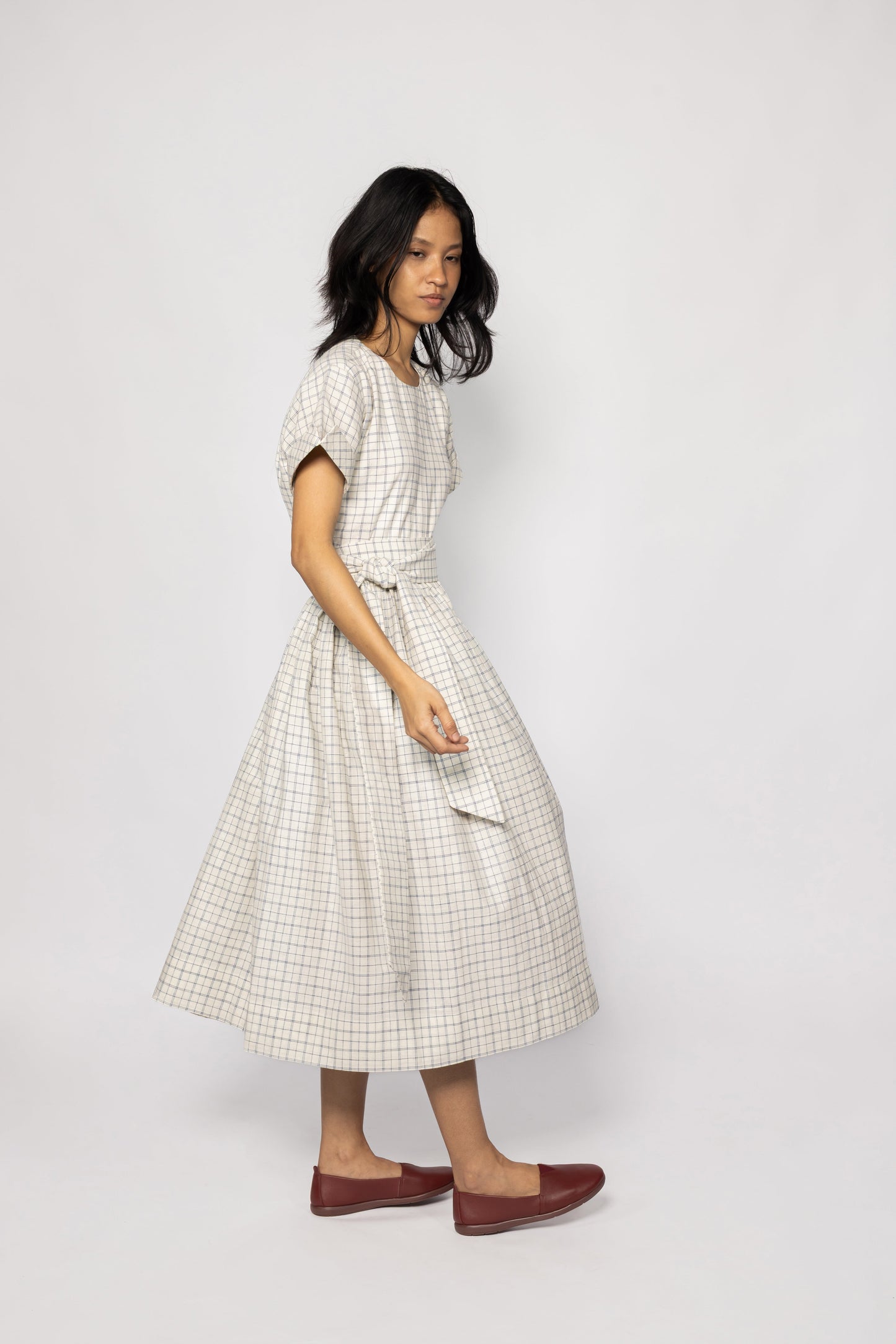 Plains Design Letter Dress - side profile  of beige checkered dress with detachable cloth belt paired with brown leather shoes