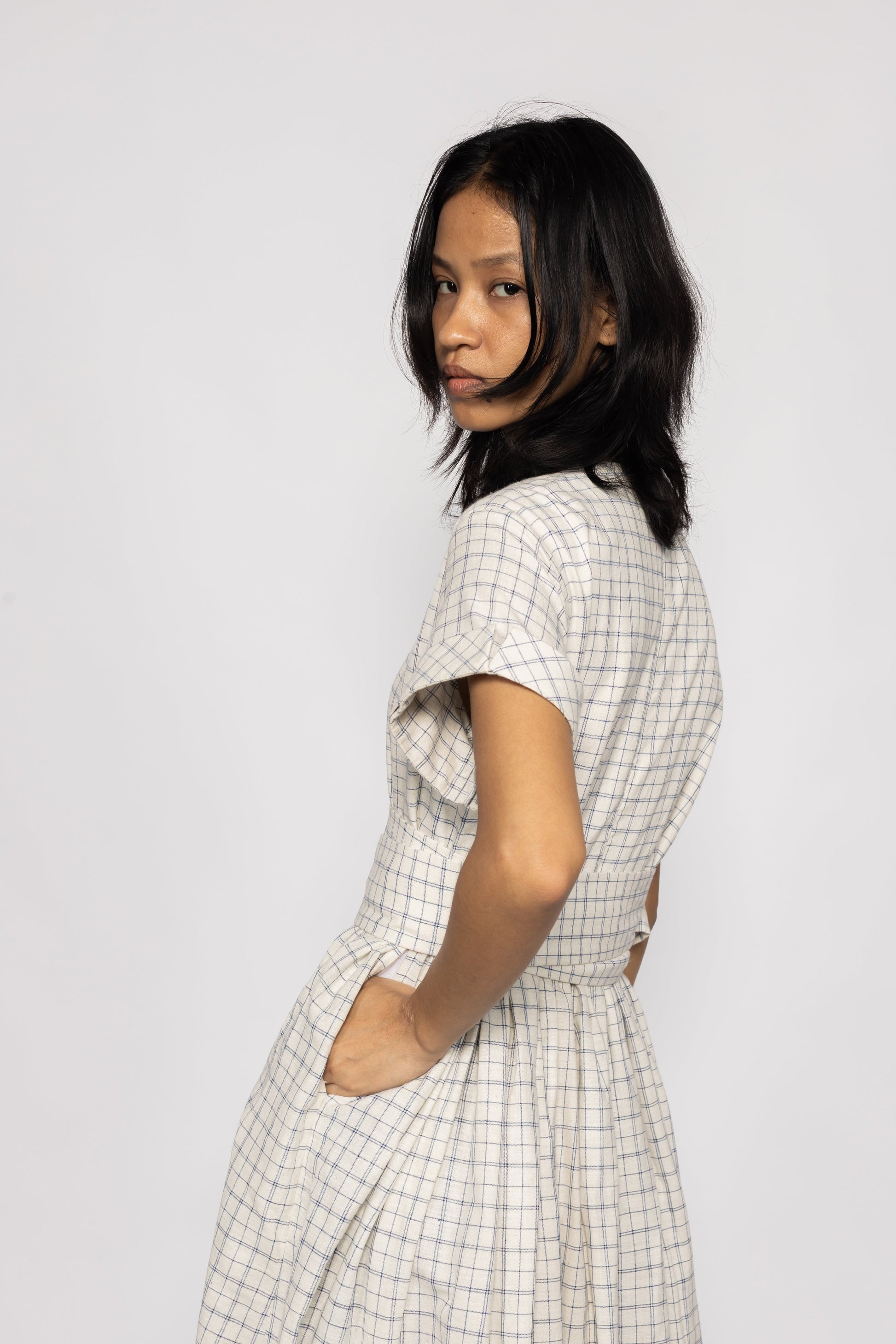 Plains Design Letter Dress - Front half side profile of handwoven cotton dress in beige with checks in short sleeves.